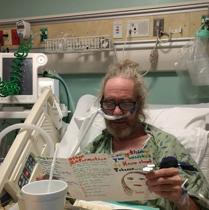 Man in a hospital bed reading a handmade card 