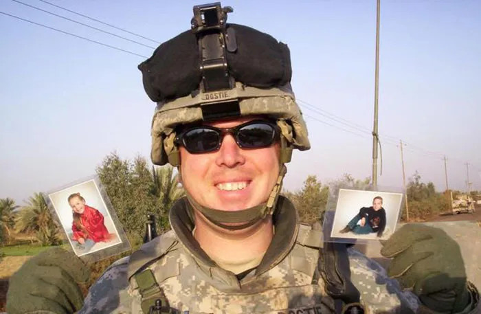 A soldier holding pictures of his kids in his hands 