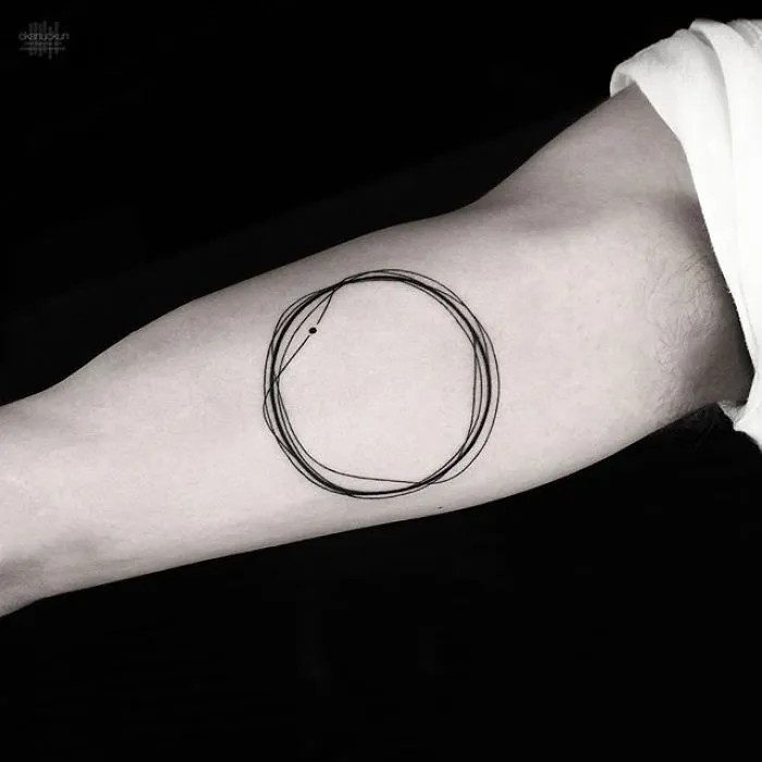 Geometric tattoo by Turkish artist Okan Uçkun featuring overlapping circular lines on an arm.