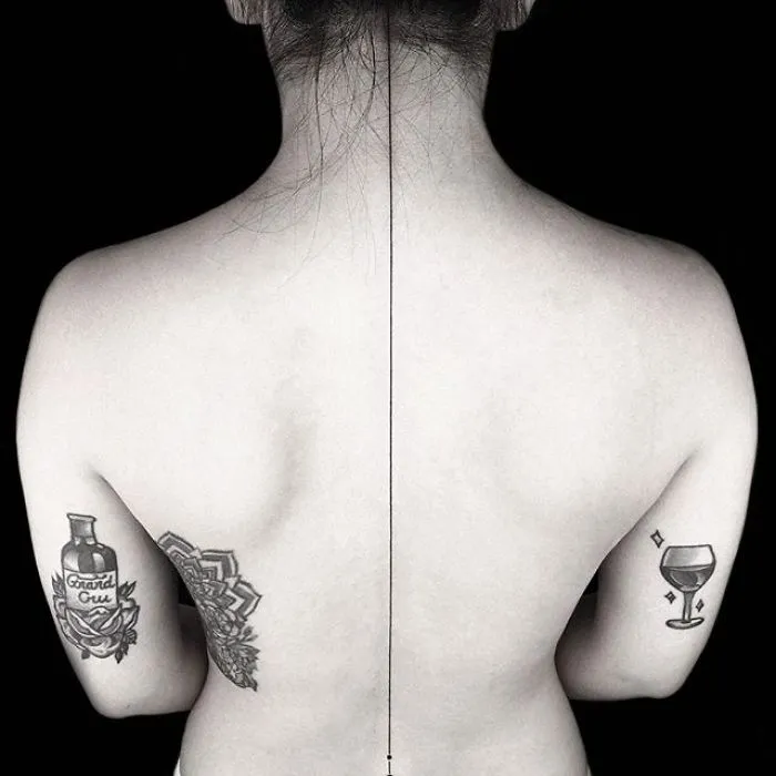 Back view with geometric tattoos by Turkish artist Okan Uçkun, featuring symmetrical designs on both shoulders.