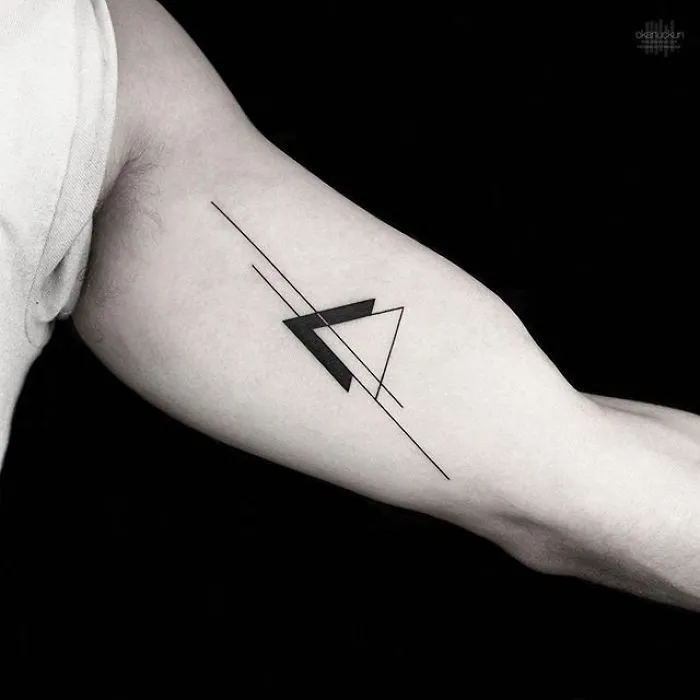 Geometric tattoo on arm featuring intersecting lines and a triangle by Turkish artist Okan Uçkun.