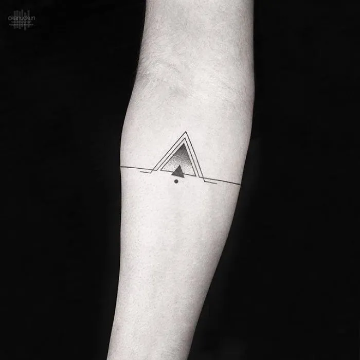 Geometric tattoo with triangle design by Turkish artist Okan Uçkun on a forearm.