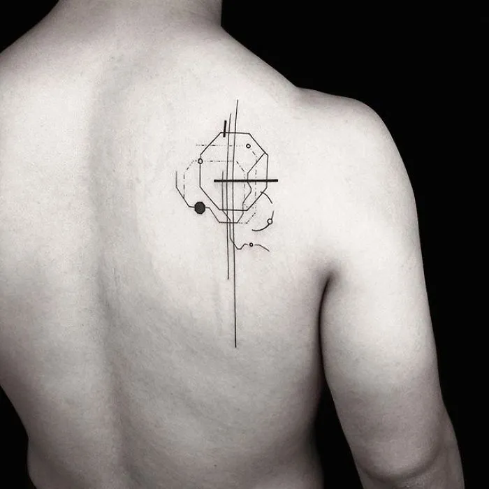 Geometric tattoo by Turkish artist Okan Uçkun on a person's back, showcasing intricate lines and shapes.
