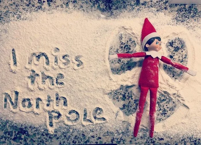 Elf On The Shelf making a snow angel in flour with I miss the North Pole written nearby, creative holiday mischief idea.