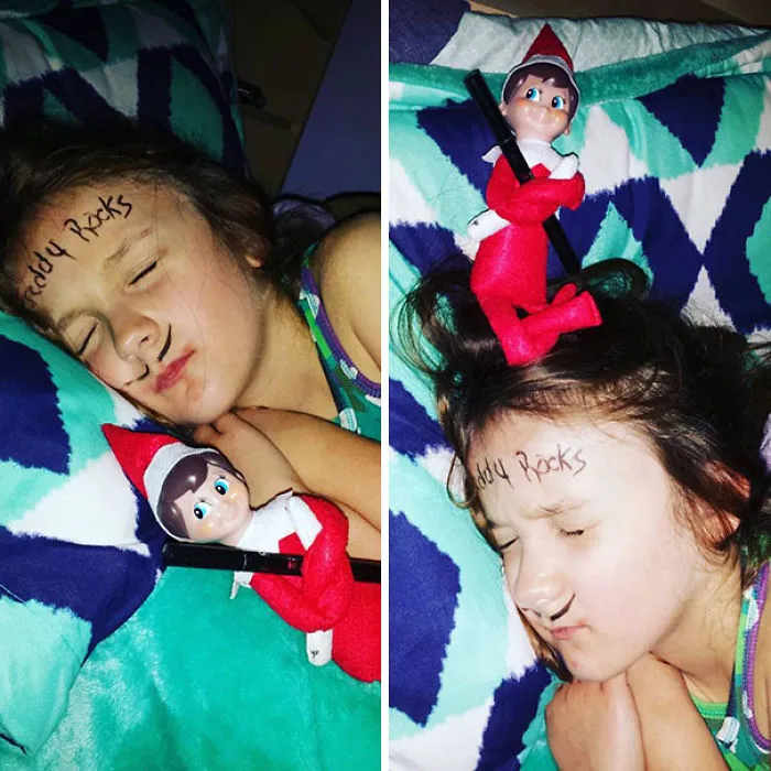 Elf On The Shelf prank with elf holding marker beside sleeping child with Freddy Rocks on forehead and mustache drawn.