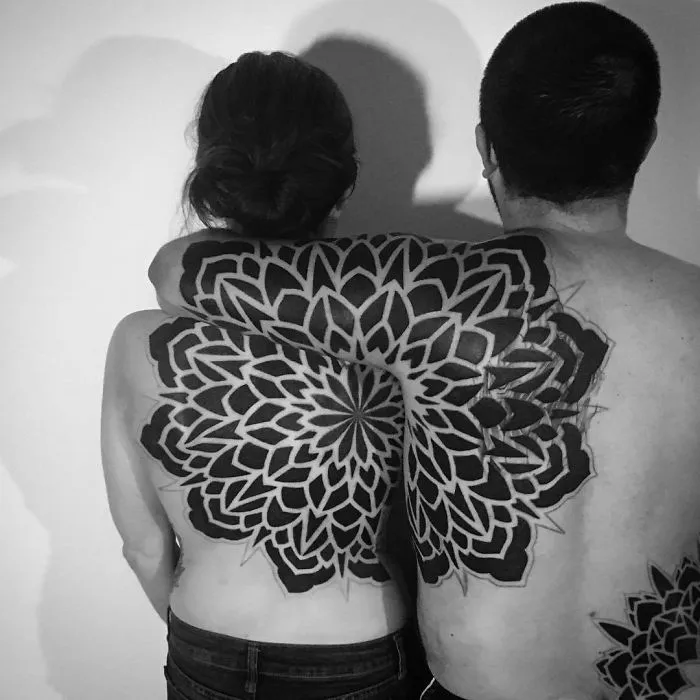 Couple with matching mandala tattoos on their backs, showcasing intricate ink patterns and tattoo ideas.