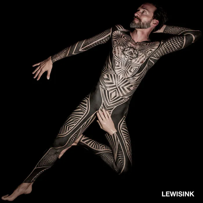 Man with intricate full-body tattoos, showcasing unique ink designs.