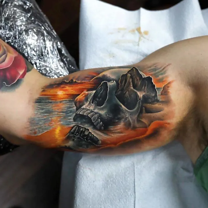 Arm tattoo featuring a detailed skull with a fiery landscape background, perfect for any ink lover.