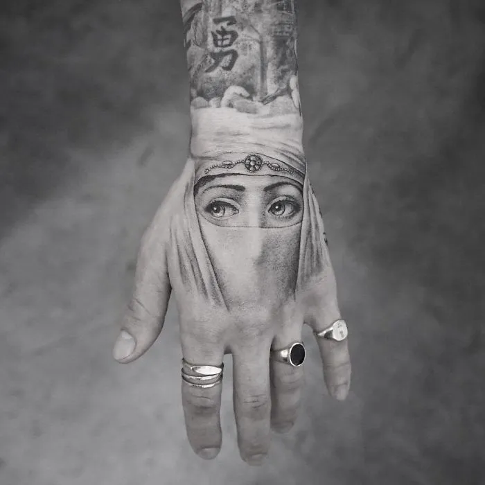 Hand tattoo featuring a detailed eye design, adorned with rings; a unique idea for every ink lover.