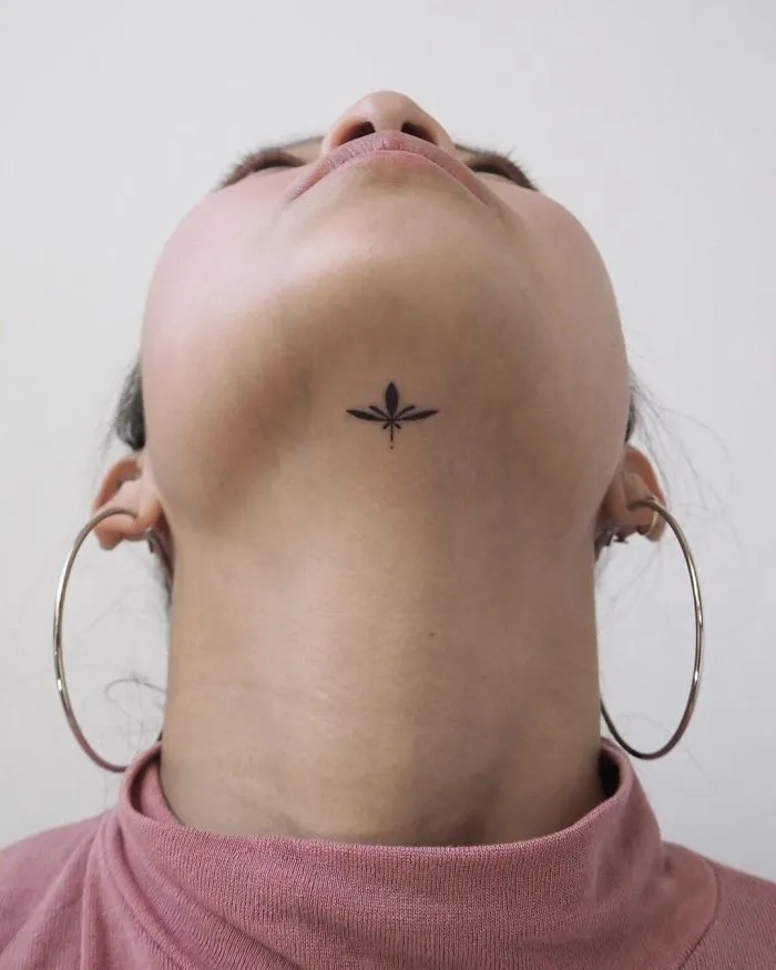 Minimalist tattoo on a person's throat, showcasing a simple, elegant design for ink lovers.