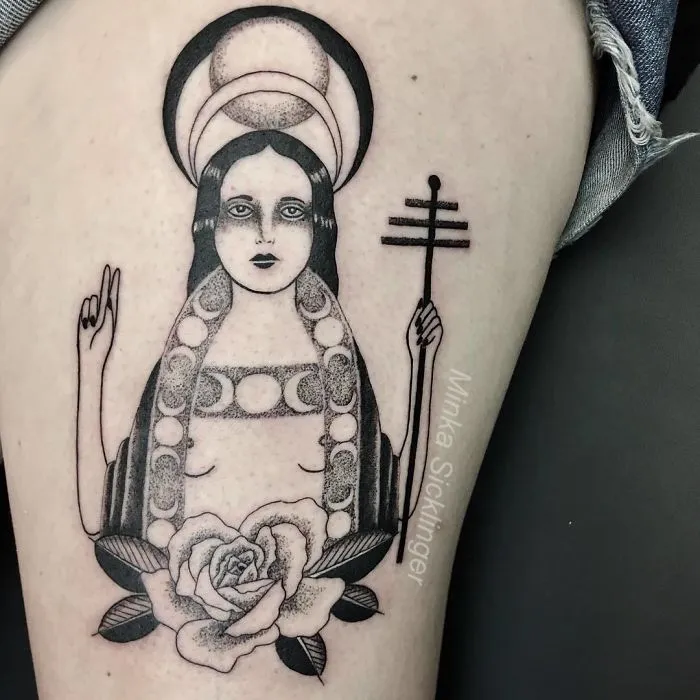 Tattoo of a saint-like figure holding a cross, with a halo and rose detail, ideal for ink lovers.