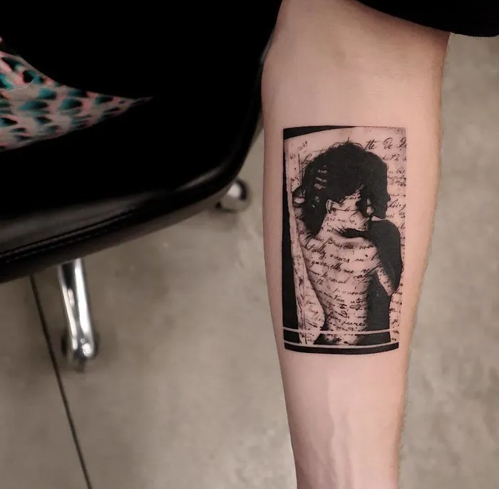 Arm with a detailed tattoo of a woman surrounded by script, perfect for ink lovers seeking unique tattoo ideas.