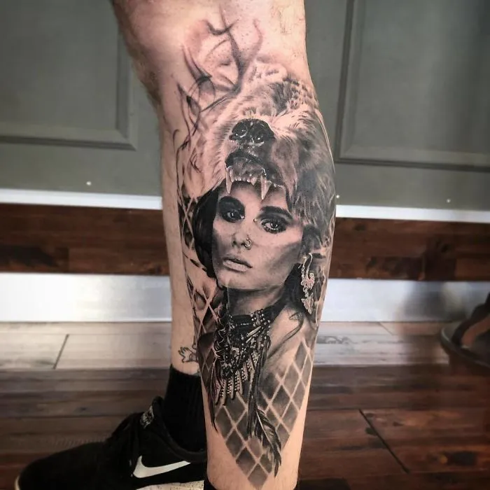 Leg tattoo featuring a woman's face with a tribal necklace and bear head design for ink lovers.