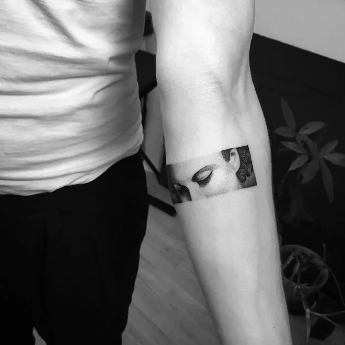 Arm tattoo of a serene face, grayscale design, perfect for ink lovers seeking unique tattoo ideas.