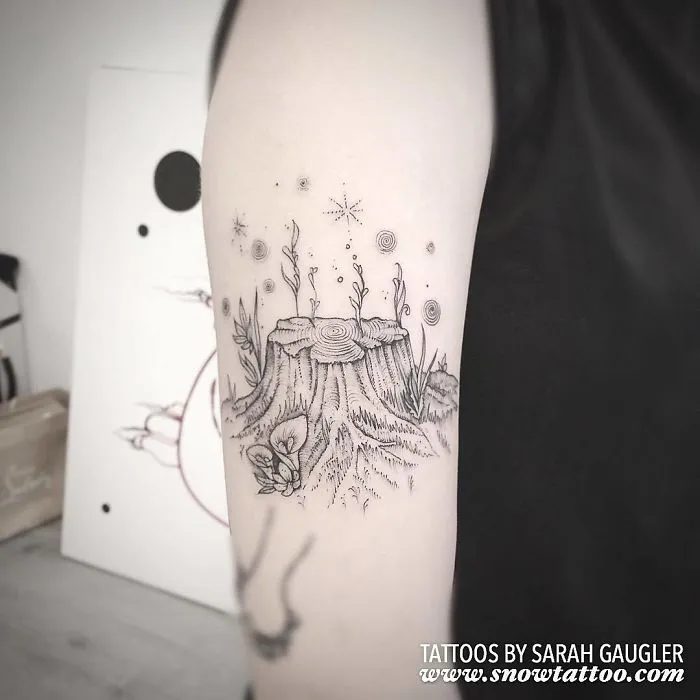 Nature-themed tattoo on arm featuring a tree stump with mushrooms and stars, ideal for every ink lover seeking inspiration.