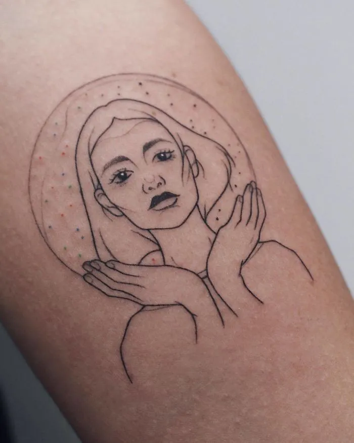 Line art tattoo of a woman's face with hands framing her, dotted halo background. Ideal tattoo inspiration for ink lovers.