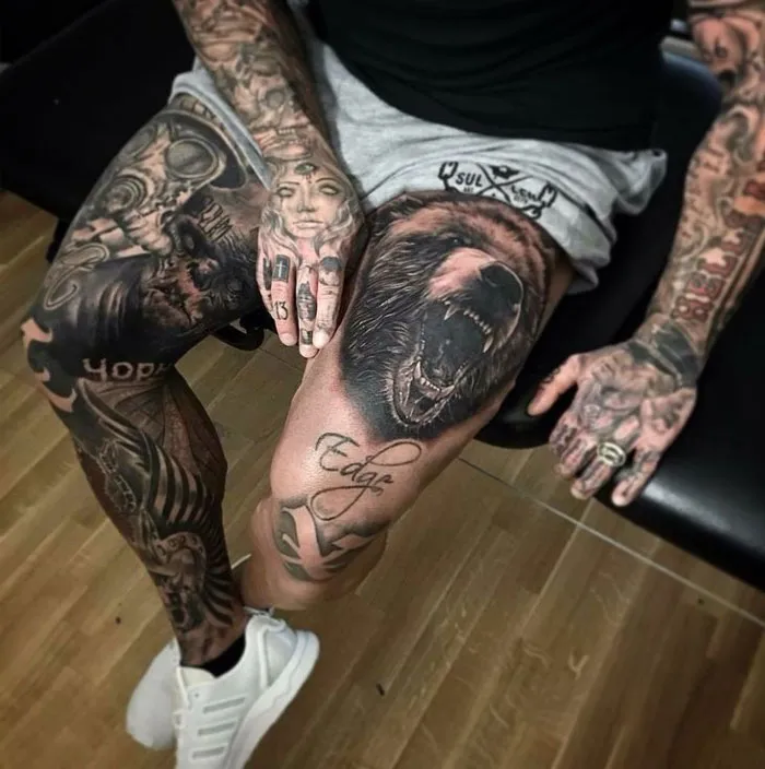 Man showcasing intricate tattoo ideas with detailed leg and hand ink designs.