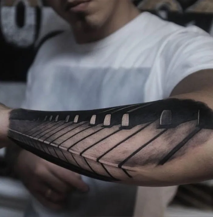 Forearm tattoo with piano keys, showcasing creative tattoo ideas for ink lovers.