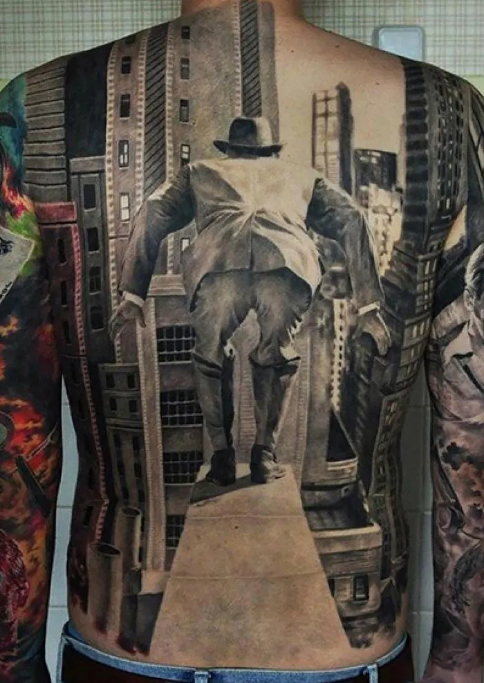 Full-back tattoo depicting a surreal cityscape with a man in a suit, perfect for every ink lover seeking creative ideas.