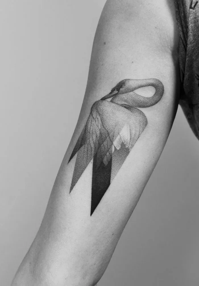 Swan tattoo design on upper arm showcasing unique geometric elements for ink lovers.