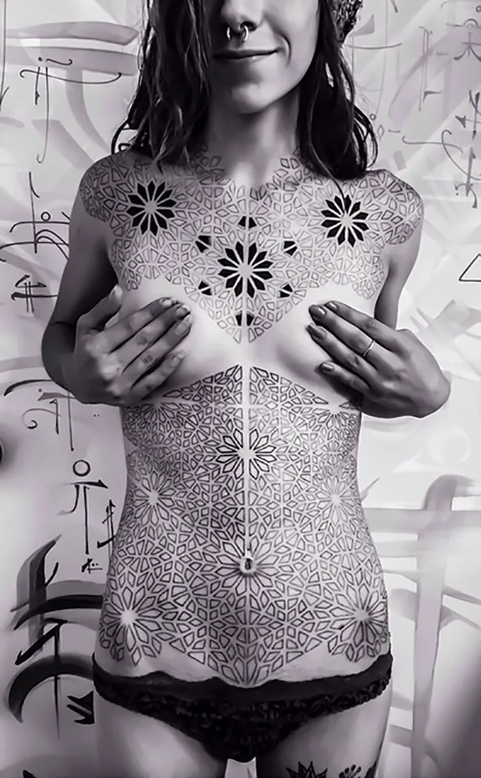 Woman displaying intricate geometric tattoos covering her upper body, showcasing tattoo ideas for every ink lover.
