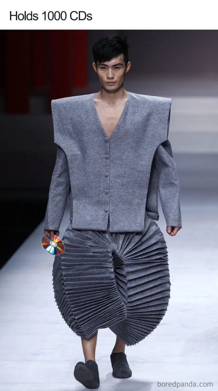 Model in gray geometric outfit, holding CDs, representing fashion disasters turned into memes.