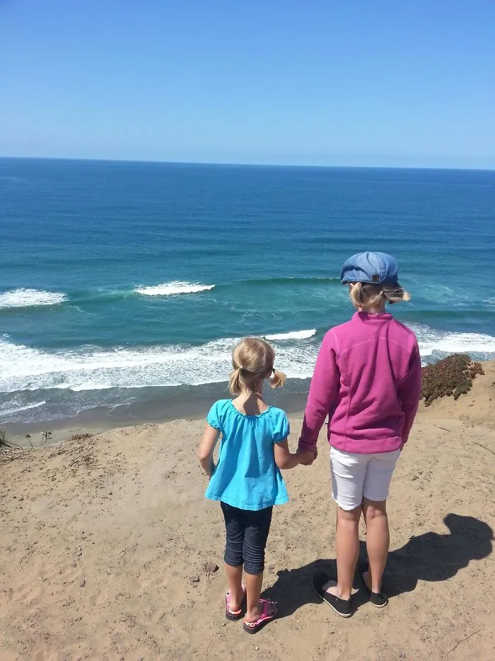 Mis hijos en un acantilado mirando al mar como si fueran gigantes