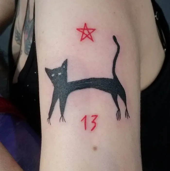 Tattoo of a minimalist black cat with the number 13 and a red star, showcasing unique style of a tattoo artist.