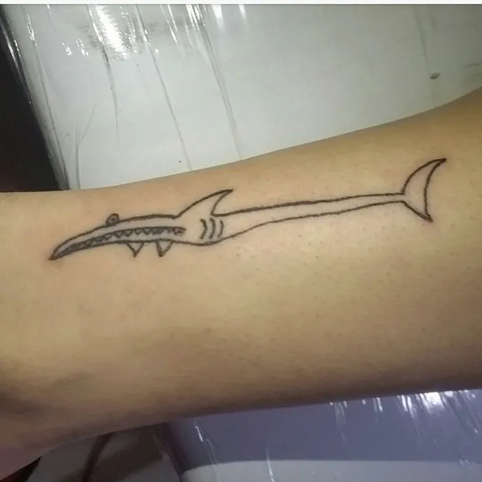Minimalist shark tattoo by an unconventional tattoo artist on a person's arm.