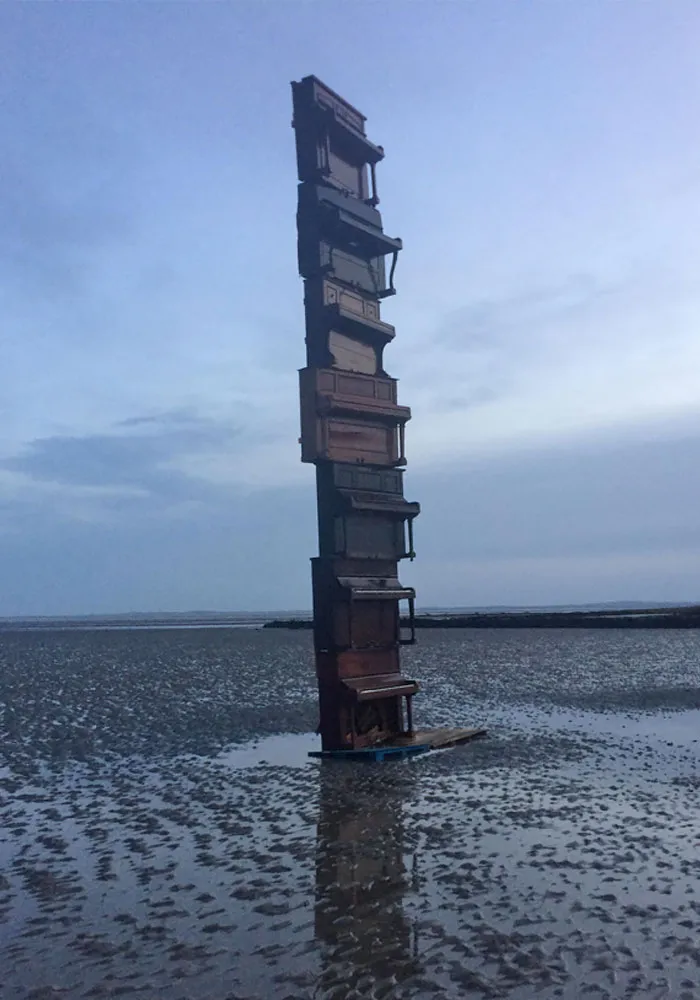 Pianos apilados en una playa con marea baja