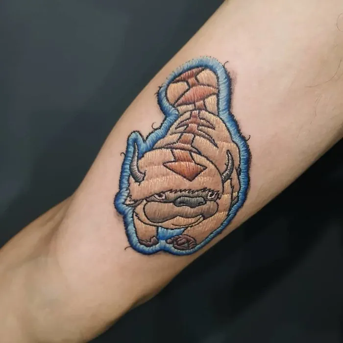 Embroidery tattoo of a buffalo from avatar on an arm, showcasing unique stitching design.