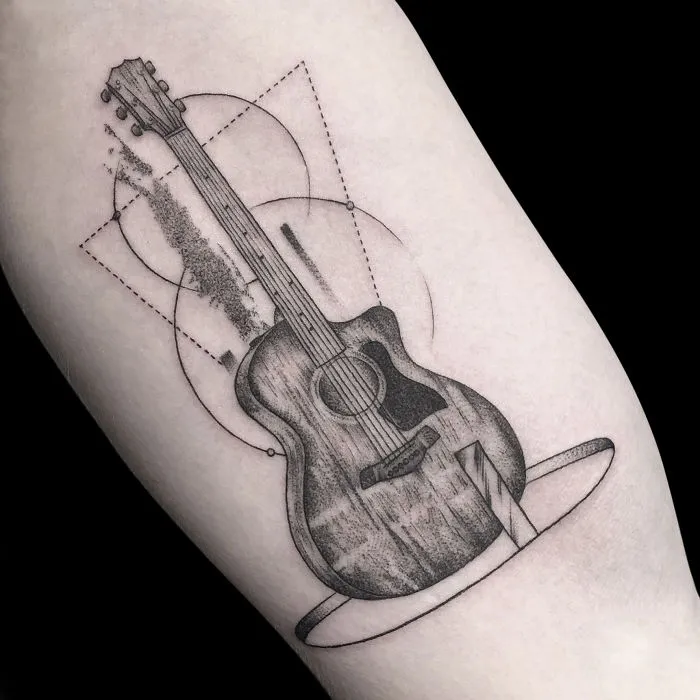 Geometric tattoo design of a guitar with circles and lines on an arm.
