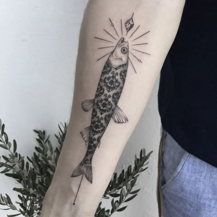 Geometric tattoo of a fish with patterned interior on arm, symbolizing personal life events.