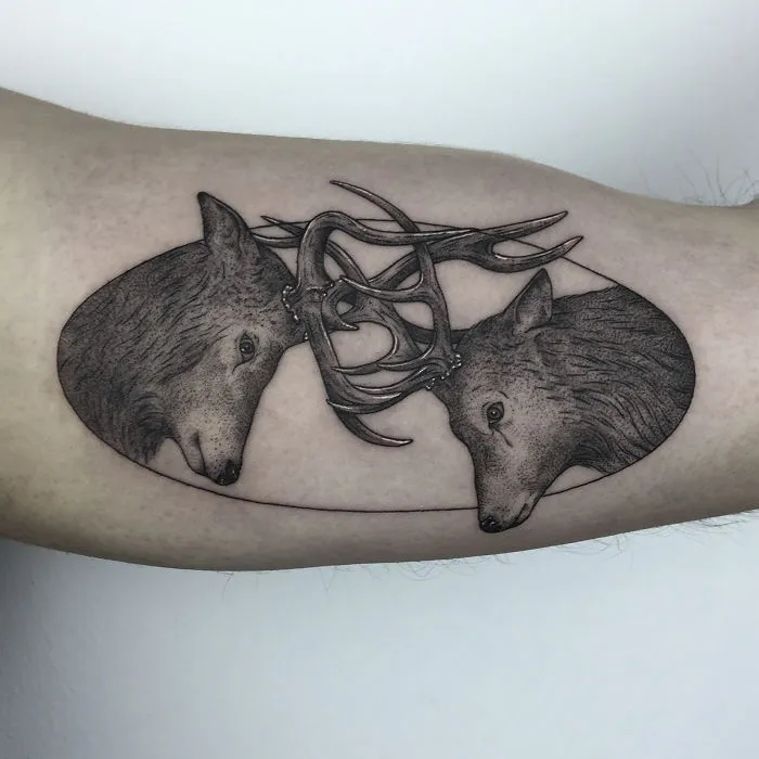 Geometric tattoo design of two animal heads with intertwining antlers, symbolizing life events.