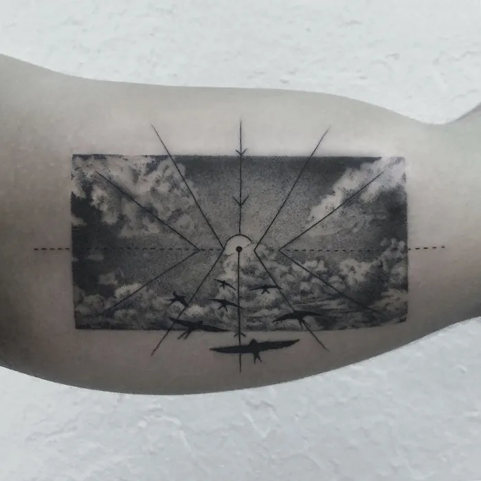 Geometric tattoo design depicting planes flying through stormy clouds with radial lines on a person's arm.
