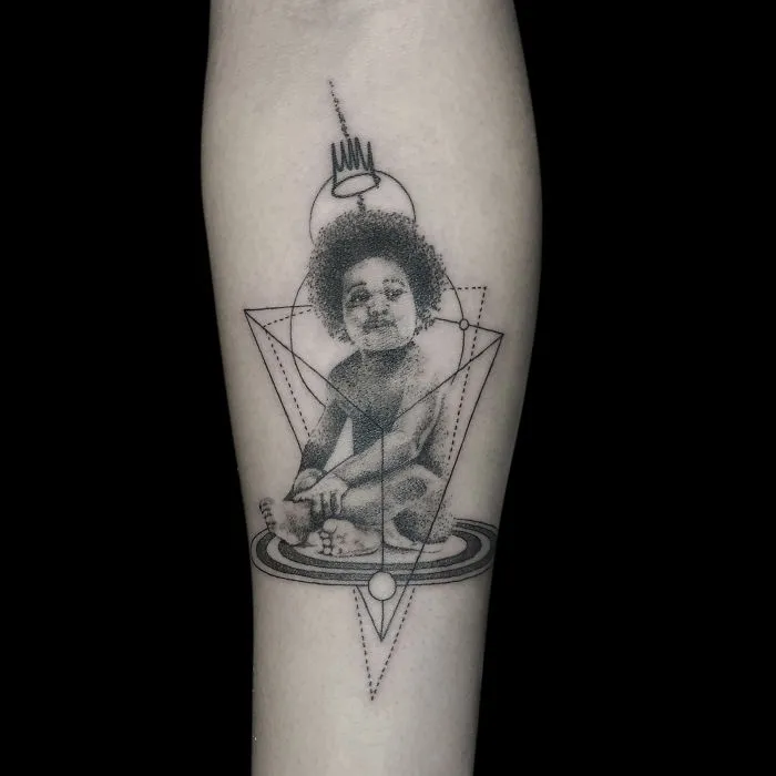 Geometric tattoo design of a child seated within complex shapes, symbolizing life's events and milestones.