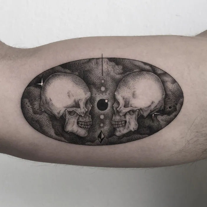 Geometric tattoo design featuring two skulls and abstract elements on inner arm.