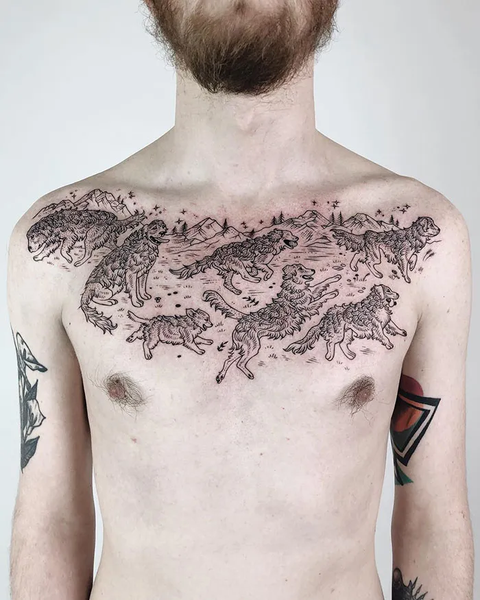 Chest tattoo featuring intricate designs of wolves and mountains.