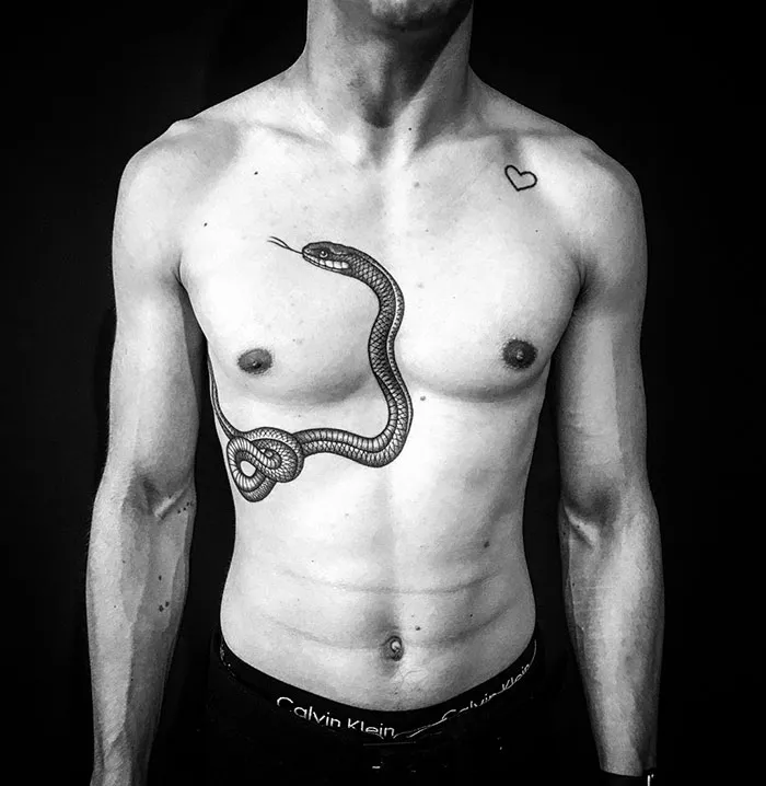 Man with intricate snake chest tattoo, showcasing incredible tattoo ideas.