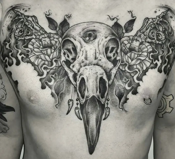 Chest tattoo featuring a detailed raven skull with ornamental designs.
