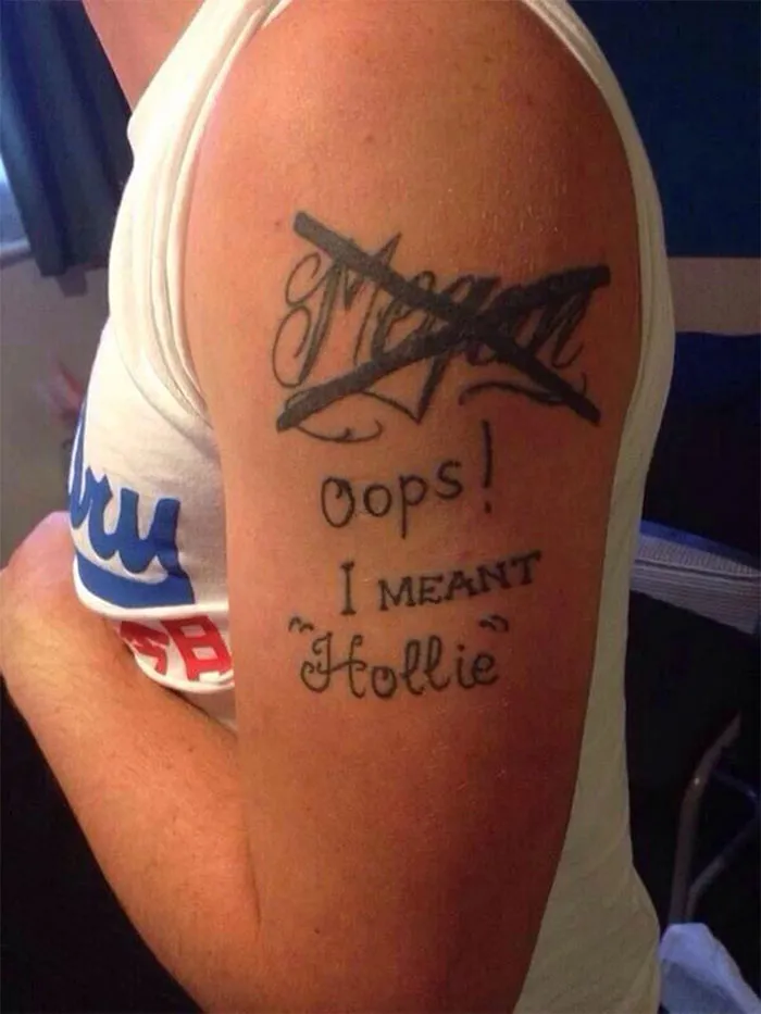 Tattoo cover-up with crossed-out name and "Oops! I meant Hollie" text on arm.