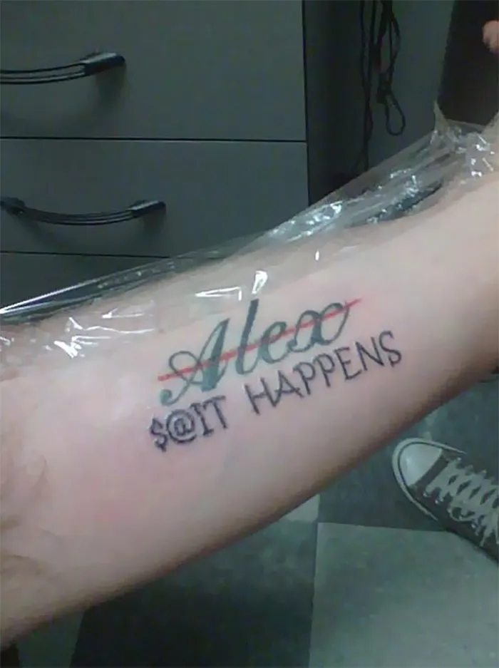 Tattoo cover-up with crossed-out name and phrase on a person's arm.