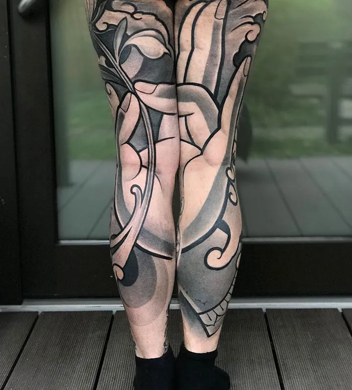 Leg sleeve tattoos with abstract black and gray designs covering both legs.