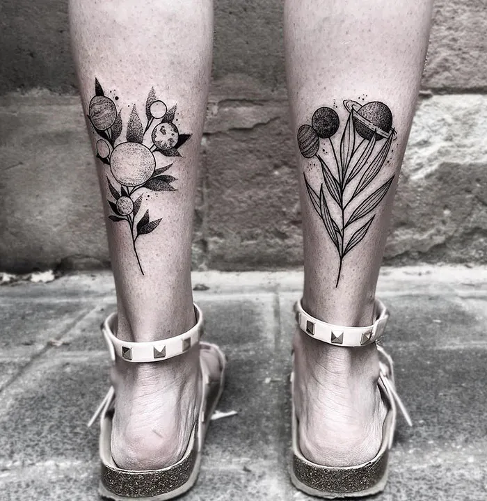 Floral leg sleeve tattoos featuring planets and leaves on the back of calves, showcased in stylish sandals.