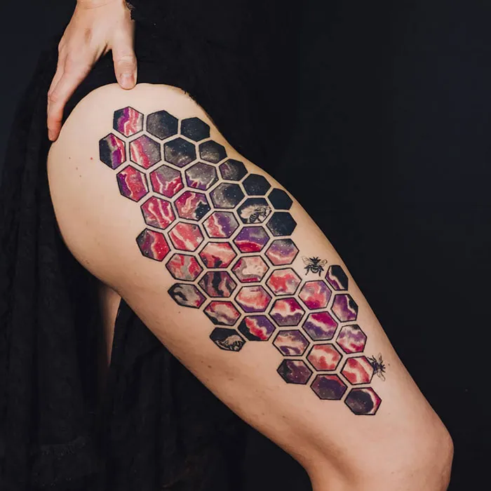 Colorful hexagon-patterned leg sleeve tattoo with bees and abstract designs.