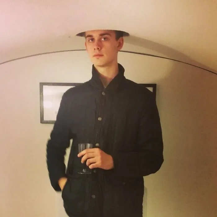 Tall person standing under a low ceiling opening, illustrating everyday struggles of tall people in a humorous way.