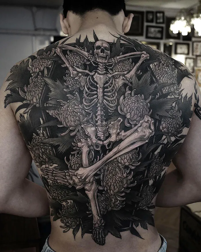 Intricate back tattoo featuring a skeleton surrounded by floral designs, showcasing an impressive masterpiece.
