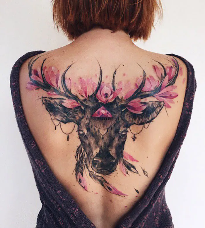 Impressive back tattoo of a deer with pink flowers, showcasing artistic mastery.