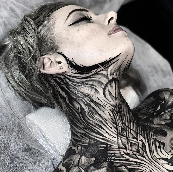 Creative neck tattoo art with intricate black ink design on woman.