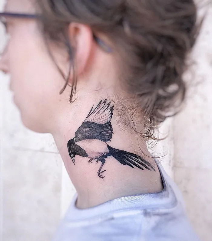 Neck tattoo of a bird in flight on a person's skin, showcasing creative inking style.